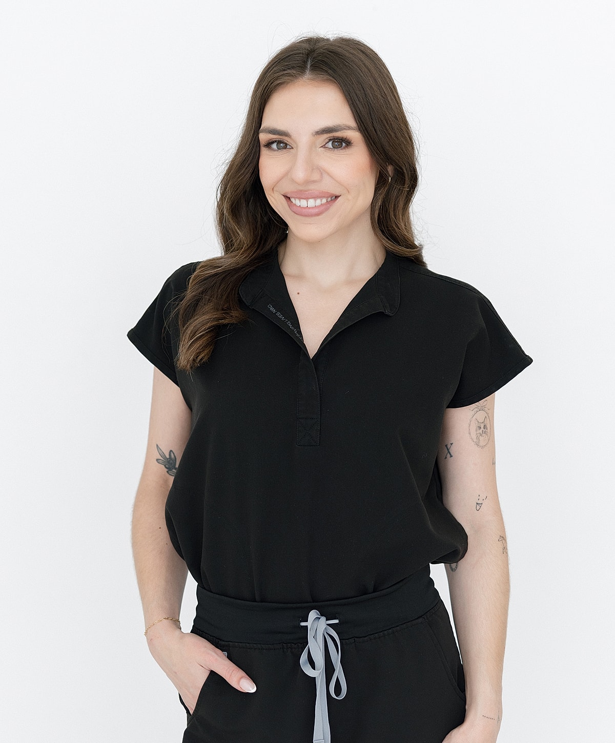 Smiling woman in a black outfit against white background.