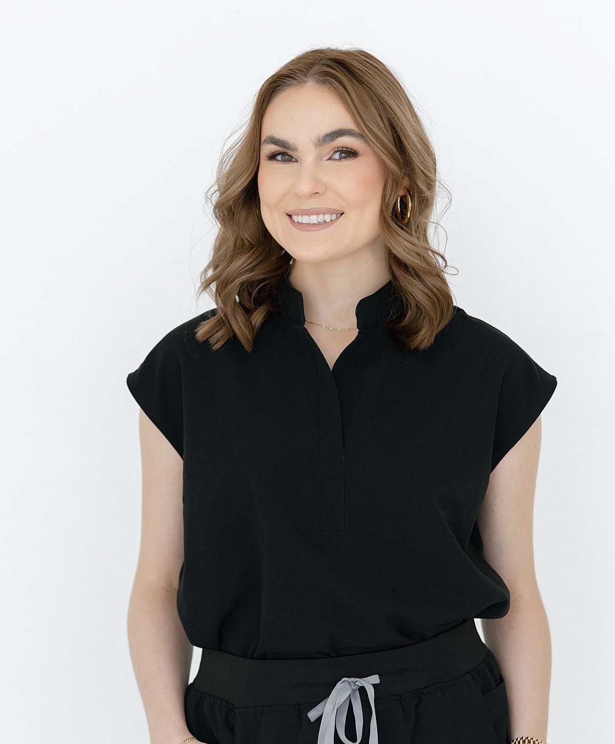 Smiling woman in black top against white background.