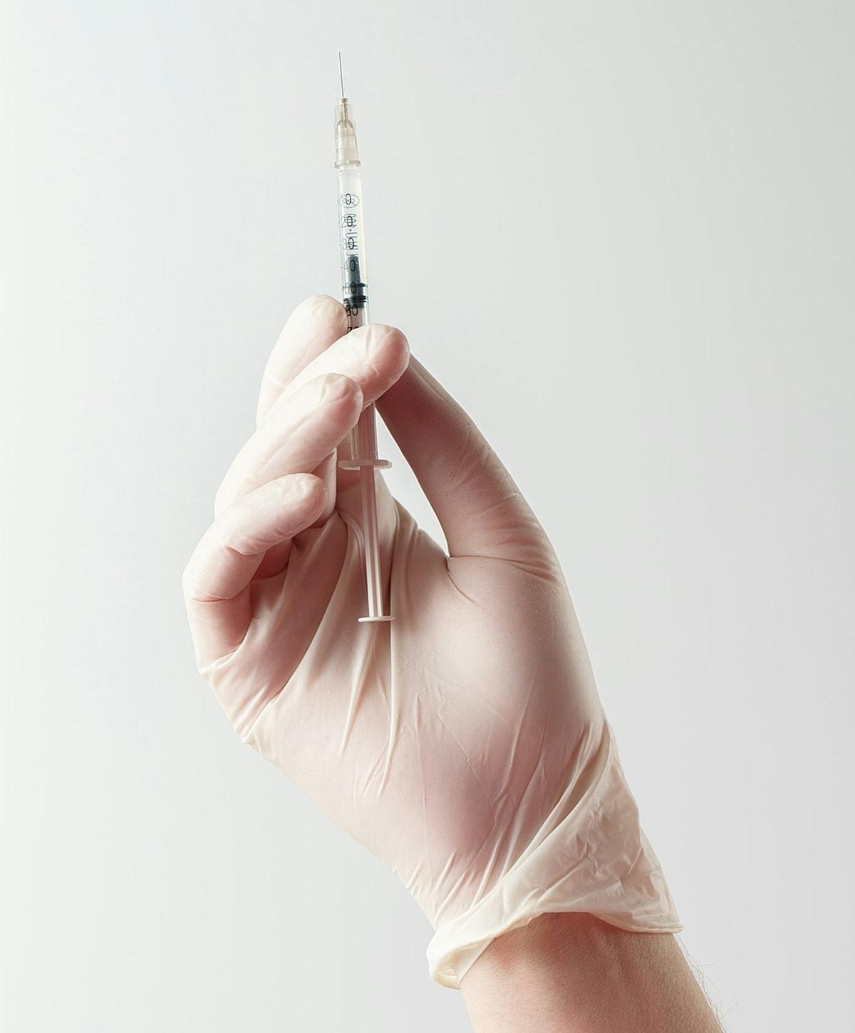 Gloved hand holding a syringe.