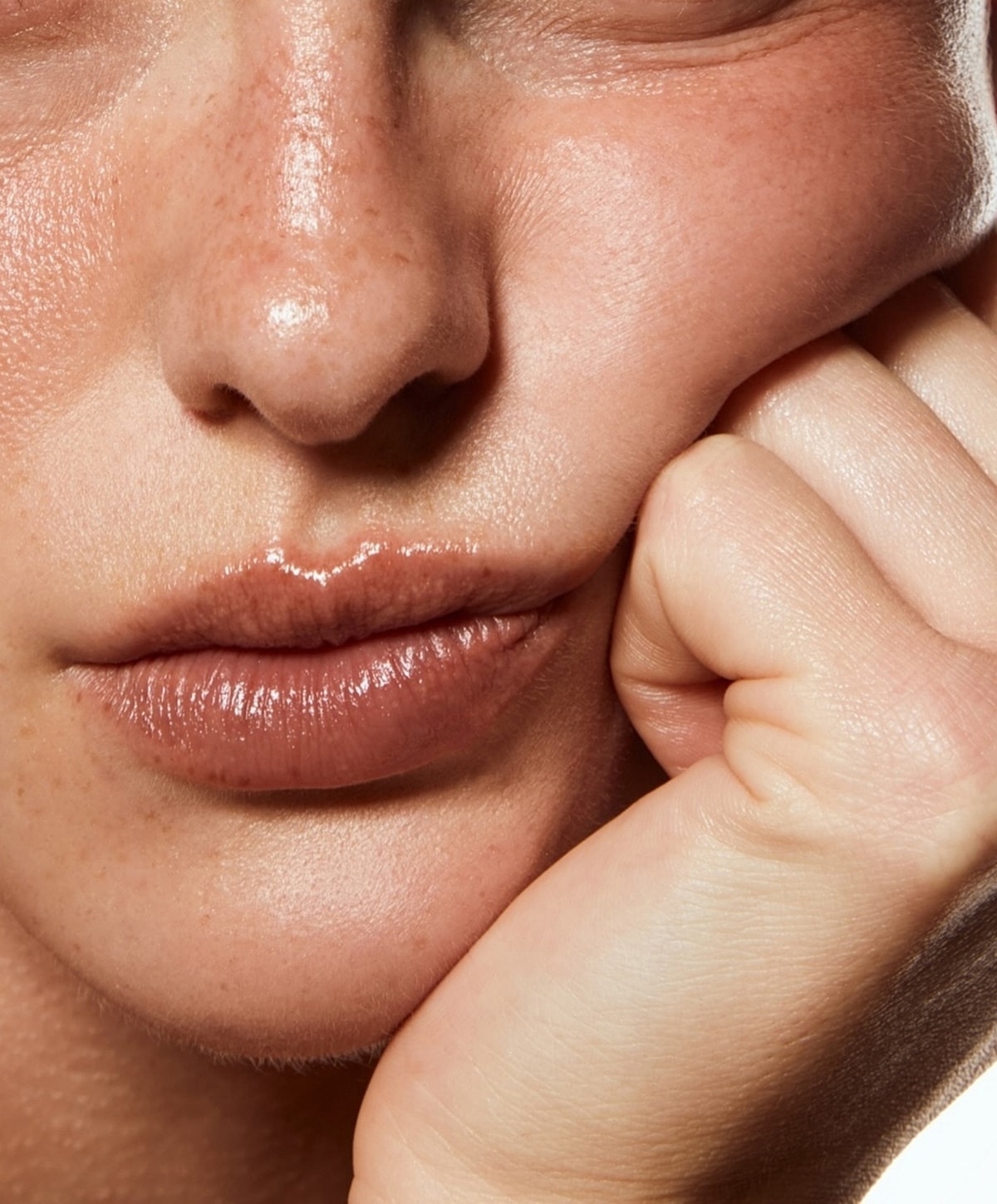 Close-up of lips and hand resting on face.