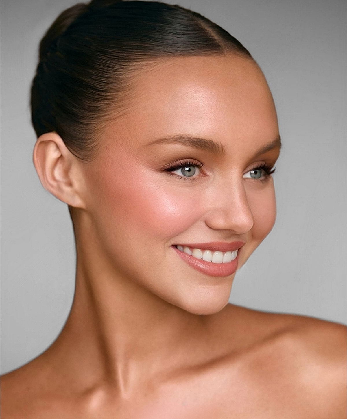 Smiling woman with a smooth complexion and hairstyle.