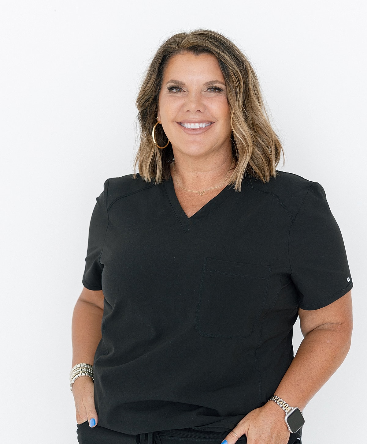 Smiling woman in black scrubs, hand on hip.