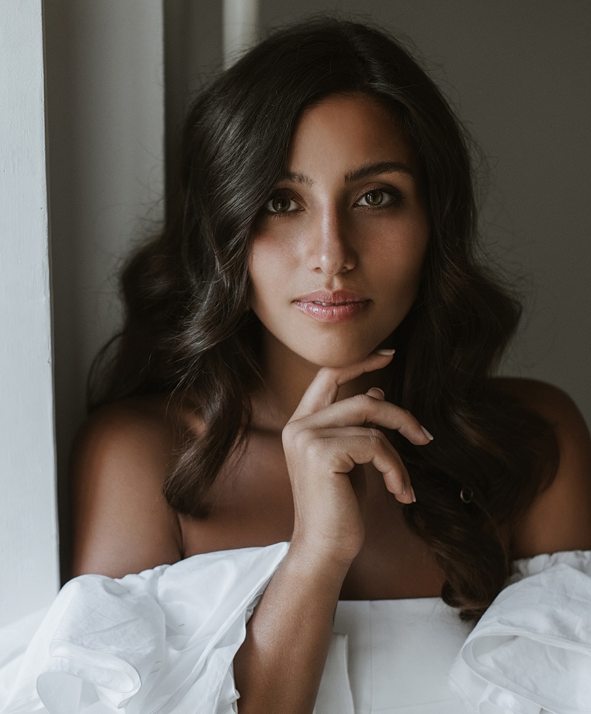 Woman with long hair, thoughtful expression, white blouse.