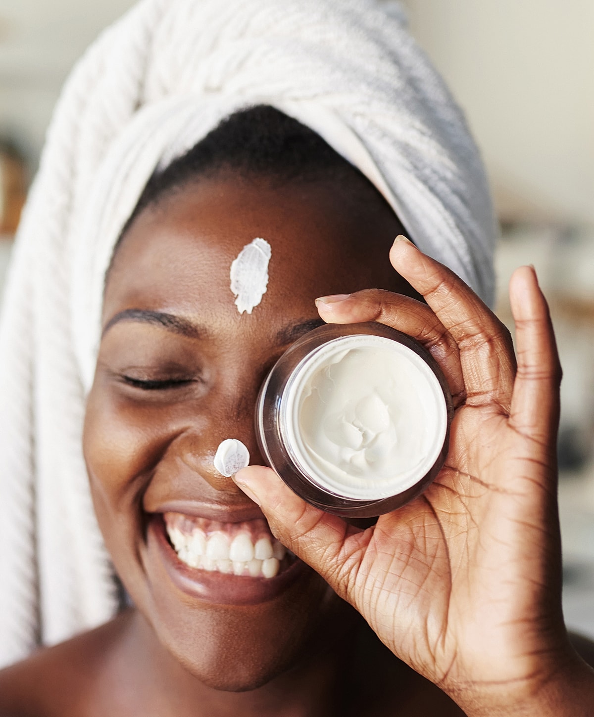 Smiling woman applying moisturizer to her face