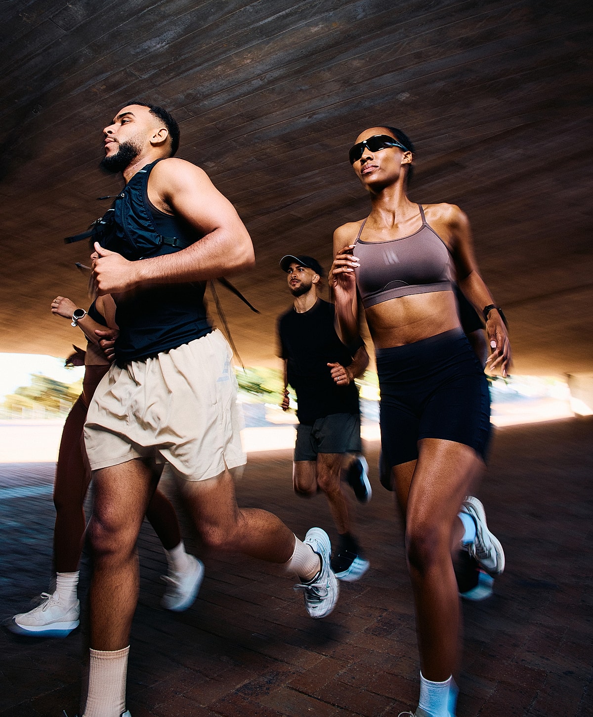 Group of runners under an overpass, dynamic motion.