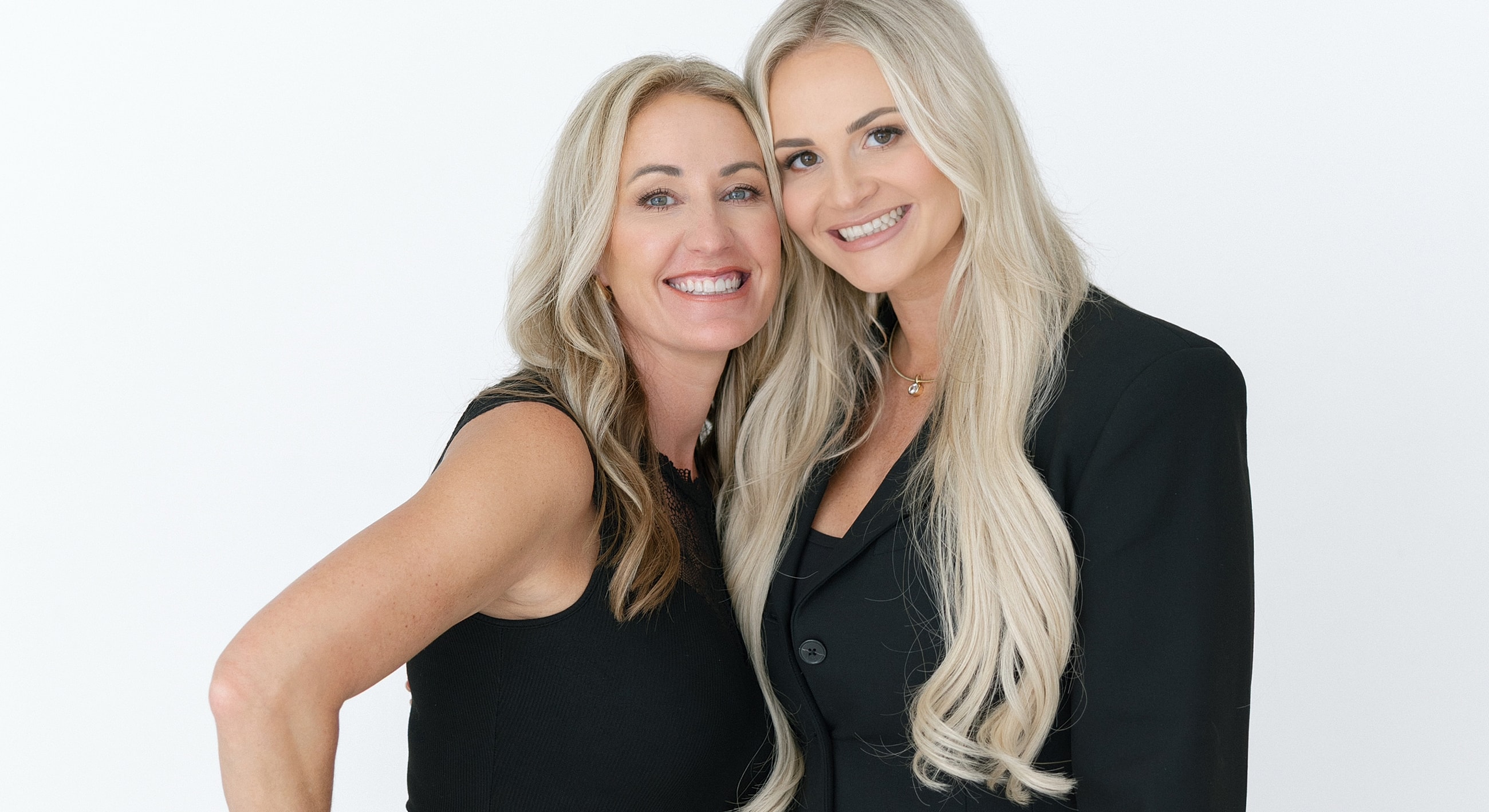 Two women smiling together against a white background