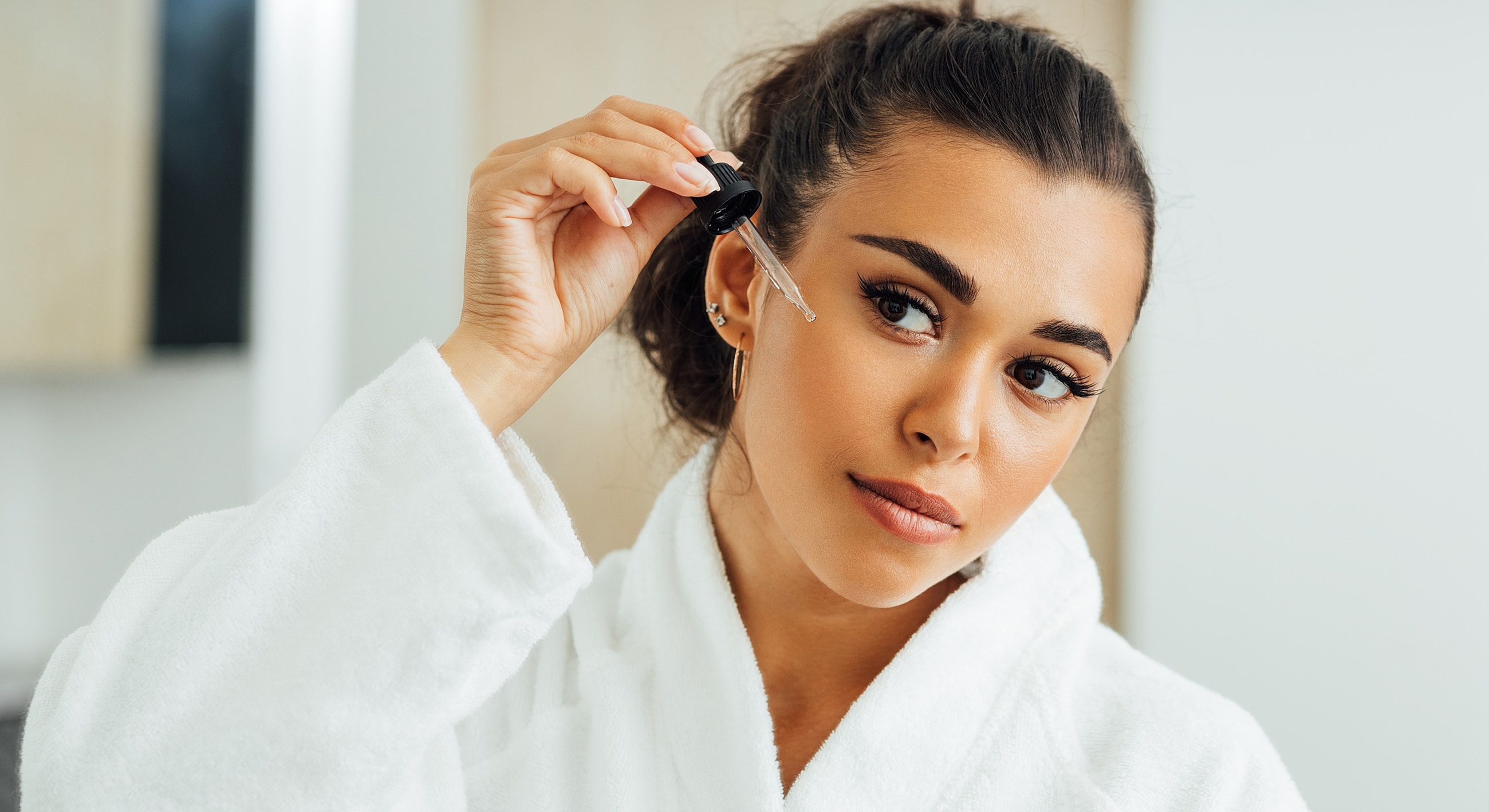 Woman applying serum in a bathrobe.